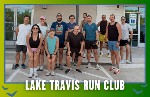 A group of thirteen people in athletic wear smile outside a building, posed for a group run. Text at the bottom reads “Lake Travis Run Club” over a green and blue border with bat graphics, highlighting the kickoff week atmosphere reminiscent of the Leanderthal Runners Club spirit. Austin Marathon Half Marathon & 5K