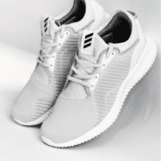 A pair of light gray athletic sneakers with white soles and laces, featuring a subtle stripe pattern on the sides and a striped design on the tongue—an ideal upgrade to your running gear and a must-have for any training checklist. Austin Marathon Half Marathon & 5K