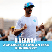 A man running in a race, wearing a white shirt and cap, is featured in the image. The text at the bottom reads, “GIVEAWAY: 2 CHANCES TO WIN AN LSKD RUNNING KIT.” Blue graphics and blurred runners set the background, emphasizing your opportunity to win exclusive prizes—don’t miss out on this exciting giveaway!. Austin Marathon Half Marathon & 5K
