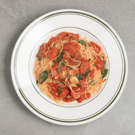A bowl of spaghetti tossed with cherry tomatoes, basil, and garlic, perfect for pre-run pasta. Austin Marathon Half Marathon & 5K